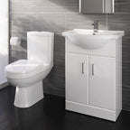 A modern bathroom features the iBathUK Bathroom Ceramic Suite: a vanity sink unit with soft-close doors and a close-coupled toilet, both in white, set against gray tiled walls and a dark floor with a wall-mounted toilet paper holder.