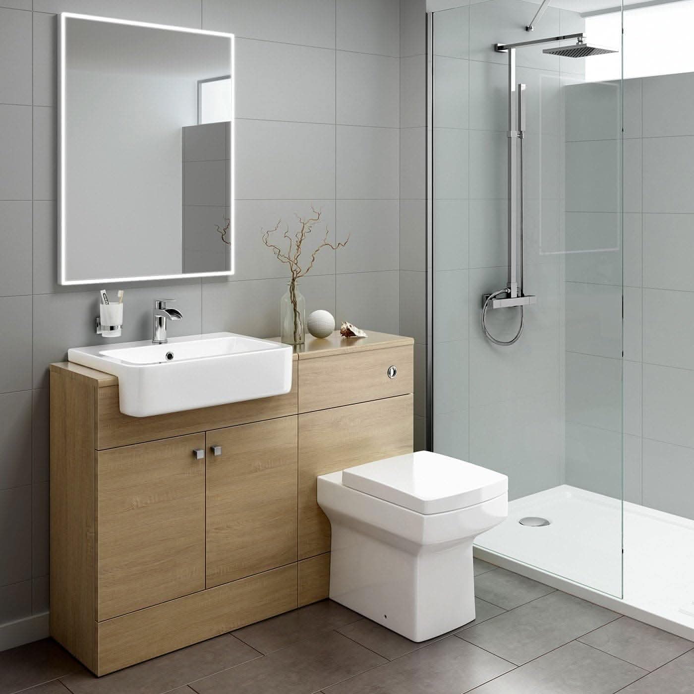 Modern bathroom upgrade with a wooden vanity, square white sink, and the iBathUK Harper Back To Wall WC Unit beside a glass shower. A large illuminated mirror hangs above and a decorative branch in a vase sits on the countertop.