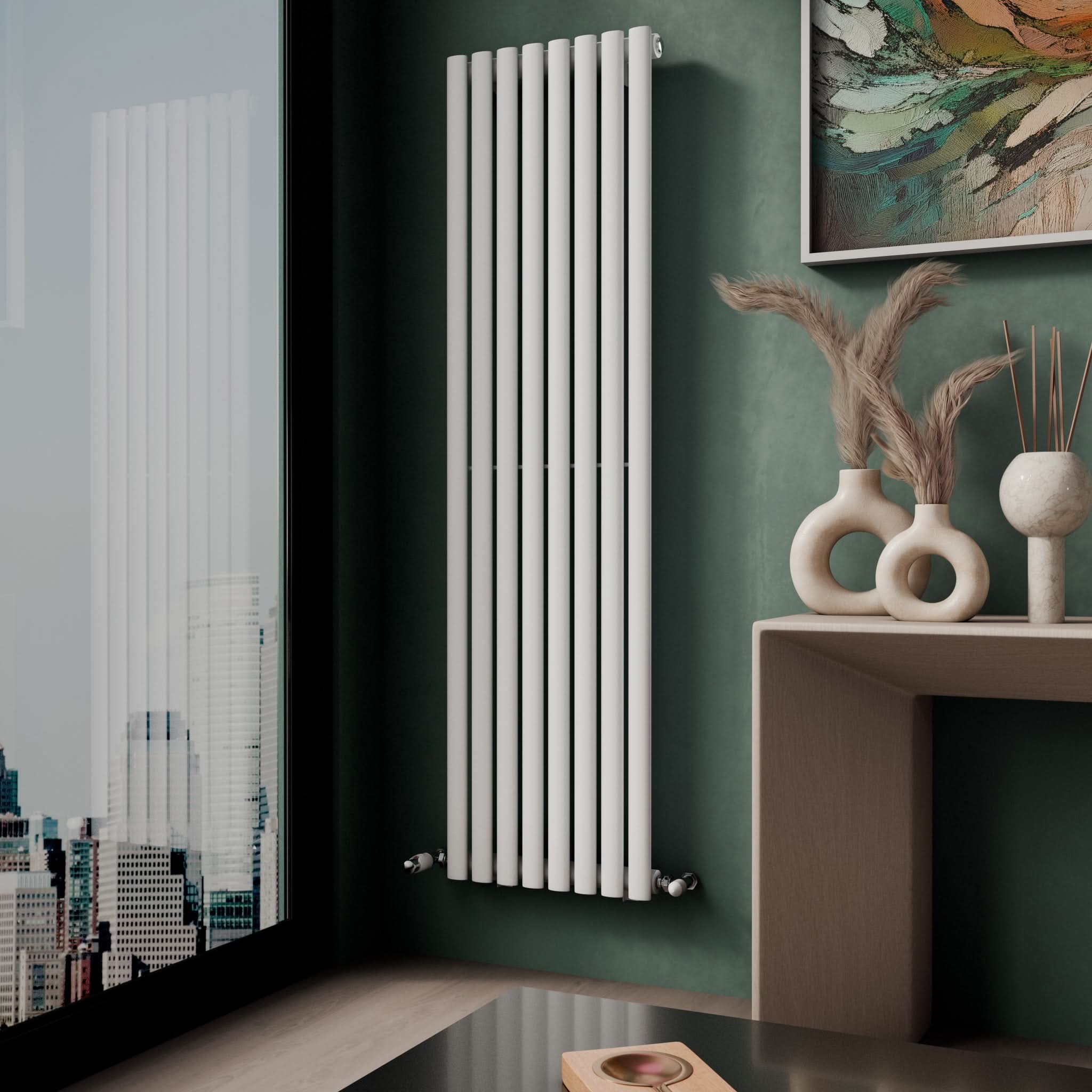 A modern room features the iBathUK Princia Vertical Single Oval Panel Radiator on a green wall, a wooden shelf with decorative vases and dried grasses, and a large window overlooking the city.